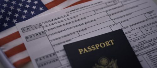 U.S. standard certificate of live birth application form next to American flag and Passport of USA. - birth right citizenship concept